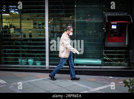 200326 -- TEHERAN, 26 marzo 2020 -- Un uomo che indossa una maschera cammina davanti a una banca chiusa a Teheran, Iran, 25 marzo 2020. Il bilancio delle vittime del nuovo coronavirus in Iran è salito a 2.234 giovedì con 157 nuove vittime, ha detto il ministero della salute. Kianush Jahanpur, capo delle pubbliche relazioni e del Centro informazioni del Ministero della salute e dell'educazione medica, ha anche annunciato 2.389 nuovi casi di COVID-19, portando il numero totale di infezioni a 29.406. Foto di /Xinhua IRAN-TEHERAN-COVID-19 AhmadxHalabisaz PUBLICATIONxNOTxINxCHN Foto Stock