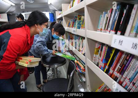 200326 -- CHANGSHA, 26 marzo 2020 -- le persone selezionano libri in una biblioteca mobile in una comunità di Changsha, provincia centrale dello Hunan della Cina, 26 marzo 2020. Di recente, le biblioteche mobili a Changsha hanno ripreso a funzionare in mezzo a misure di prevenzione e controllo delle epidemie. Mobile Library è un progetto della Changsha Library che prende autobus come vettori per visitare comunità, scuole, aziende, cantieri e altre aree della città mensilmente e fornisce servizi di lettura, consulenza, prestito e restituzione di libri. CHINA-HUNAN-CHANGSHA-MOBILE LIBRARY CN CHENXZEGUO PUBLICATIONXNOTXINXCHN Foto Stock