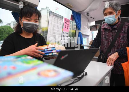 200326 -- CHANGSHA, 26 marzo 2020 -- Un membro dello staff aiuta un residente a restituire libri in una biblioteca mobile in una comunità di Changsha, provincia centrale dello Hunan della Cina, 26 marzo 2020. Di recente, le biblioteche mobili a Changsha hanno ripreso a funzionare in mezzo a misure di prevenzione e controllo delle epidemie. Mobile Library è un progetto della Changsha Library che prende autobus come vettori per visitare comunità, scuole, aziende, cantieri e altre aree della città mensilmente e fornisce servizi di lettura, consulenza, prestito e restituzione di libri. CHINA-HUNAN-CHANGSHA-MOBILE LIBRARY CN CHENXZEGUO PUBLICA Foto Stock