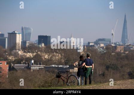 200327 -- LONDRA, 27 marzo 2020 -- le persone si coccolano mentre guardano lo skyline della città in cima a Primrose Hill a Londra, in Gran Bretagna, il 26 marzo 2020. Il governo britannico ha detto giovedì che il numero di casi confermati di COVID-19 nel paese è salito a 11.658, in quanto i decessi di un solo giorno hanno superato i 100 per la prima volta dall'epidemia della malattia. BRITAIN-LONDON-COVID-19 HanxYan PUBLICATIONxNOTxINxCHN Foto Stock