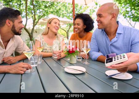 Uomo che effettua il pagamento senza contatto al bar o ristorante all'aperto con carta di credito o di debito Foto Stock