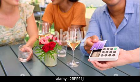 Primo piano di Man Making Contactless Payment al bar o ristorante all'aperto con carta di credito o di debito Foto Stock