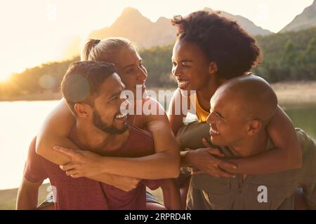 Ritratto all'aperto di Friends with Men Giving Women Piggybacks Foto Stock