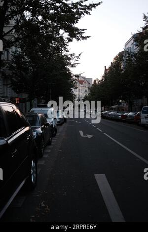 Una fila di auto parcheggiate in una strada di fronte a diversi edifici Foto Stock