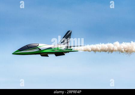 Un modello di jet radiocomandato mette in fuga una pista di fumo in un sorvolo al Popham Airfield, esposizione di modellini, Popham, Hampshire, Regno Unito Foto Stock