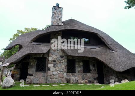 La Thatch House, una delle Case dei funghi, progettata dall'architetto Earl Young nel XX secolo, con tetto in paglia il 24 agosto 2023 a Charlevoix, M. Foto Stock