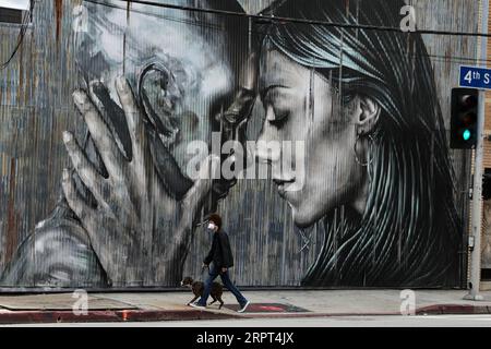 200411 -- LOS ANGELES, 11 aprile 2020 Xinhua -- Un uomo che indossa la maschera cammina il suo cane all'Art District, nel centro di Los Angeles, negli Stati Uniti, 10 aprile 2020. L'invito del sindaco di Los Angeles Eric Garcetti a indossare maschere in pubblico per rallentare la diffusione del coronavirus è stato imposto come mandato a partire dalla mezzanotte di venerdì, in base al quale tutti i lavoratori essenziali non medici e i clienti delle imprese nella seconda città più grande degli Stati Uniti sono stati tenuti a coprire i loro volti. Xinhua U.S.-LOS ANGELES-MASK-COVID-19 PUBLICATIONxNOTxINxCHN Foto Stock