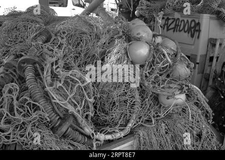 Attrezzatura per la pesca commerciale sparsi sul porto nell'affollata area di lavoro di Plymouth Fisheries. Immagine in bianco e nero. Foto Stock