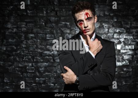 Un uomo zombie penoso con un volto sanguinoso che posa davanti alla telecamera Foto Stock