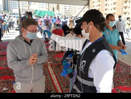 200414 -- GOVERNATORATO DI AHMADI, 14 aprile 2020 Xinhua -- Un lavoratore controlla la temperatura di un residente prima di entrare in un nuovo negozio per lo shopping nella zona di Mahboula nel Governatorato di Ahmadi, Kuwait, 14 aprile 2020. Il Kuwait ha aperto il martedì un negozio di alimentari per i residenti dell'area di Mahboula, che è sotto isolamento a causa del coronavirus. Str/Xinhua KUWAIT-AHMADI GOVERNORATO-CORONAVIRUS-APERTURA DI NUOVI NEGOZI PUBLICATIONxNOTxINxCHN Foto Stock