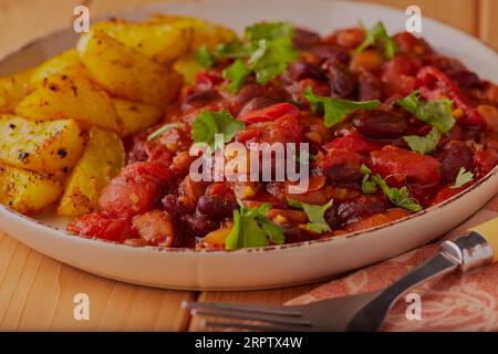 Peperoncino di pollo piccante con spicchi di patate al forno. Foto Stock