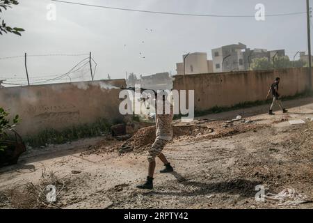 200419 -- TRIPOLI, 19 aprile 2020 Xinhua -- Un combattente del governo di accordo nazionale sostenuto dalle Nazioni Unite GNA spara la sua arma durante gli scontri con LNA dell'Esercito Nazionale libico al fronte Salah al-DIN a Tripoli, Libia, 18 aprile 2020. Le forze libiche del governo appoggiate dalle Nazioni Unite hanno dichiarato di aver lanciato 17 attacchi aerei sulle posizioni dell'esercito a Tarhuna, circa 90 chilometri a sud della capitale Tripoli, sequestrando una serie di veicoli militari. Nonostante la richiesta internazionale di cessate il fuoco in Libia, il conflitto armato mortale è continuato con vittime civili collaterali. Foto di Amru Salahuddien/Xinhua LIBIA- Foto Stock