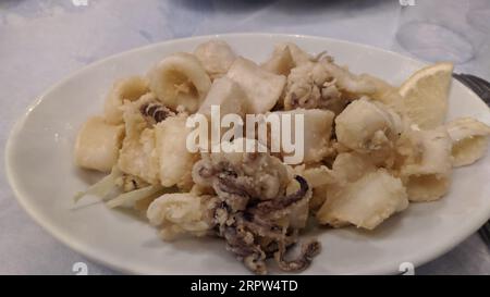 Anelli di calamari fritti antipasto di calamari impanato su padella in ghisa, su sfondo nero scuro tavolo in pietra, vista dall'alto piatto Foto Stock