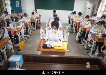 200506 -- WUHAN, 6 maggio 2020 -- gli studenti anziani studiano in un'aula con tavole trasparenti posizionate su ogni scrivania per separarsi l'un l'altro come misura precauzionale contro la velocità della COVID-19 alla Wuhan No. 23 Middle School a Wuhan, nella provincia di Hubei della Cina centrale, 6 maggio 2020. Circa 57.800 studenti nel loro ultimo anno da 121 scuole superiori e professionali sono tornati al campus mercoledì a Wuhan, la capitale della provincia di Hubei della Cina centrale e una città precedentemente duramente colpita dall'epidemia di COVID-19. CHINA-WUHAN-HIGH SCHOOL STUDENTS-CLASSES RIPRESA CN XIAOXYIJIU PUBLICATIONXNOTXINXCHN Foto Stock