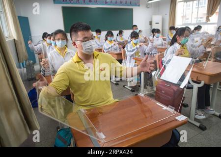 200506 -- WUHAN, 6 maggio 2020 -- gli studenti anziani aprono tavole trasparenti per collocarle sulle scrivanie per separarsi l'una dall'altra come misura precauzionale contro la diffusione della COVID-19 in un'aula della Wuhan No. 23 Middle School a Wuhan, nella provincia di Hubei della Cina centrale, 6 maggio 2020. Circa 57.800 studenti nel loro ultimo anno da 121 scuole superiori e professionali sono tornati al campus mercoledì a Wuhan, la capitale della provincia di Hubei della Cina centrale e una città precedentemente duramente colpita dall'epidemia di COVID-19. CHINA-WUHAN-HIGH SCHOOL STUDENTS-CLASSES RIPRESA CN XIAOXYIJIU PUBLICATIONXNOTXINXCHN Foto Stock