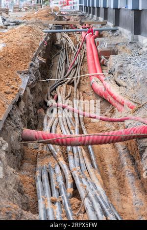 installazione di infrastrutture per cavi elettrici sotterranei. Cantiere con molti cavi di comunicazione protetti in tubi. elettrico e alta-spe Foto Stock