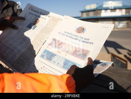 200516 -- HARARE, 16 maggio 2020 Xinhua -- Una persona guarda le illustrazioni di nuove banconote su un giornale di Harare, Zimbabwe, 16 maggio 2020. La Reserve Bank of Zimbabwe RBZ ha detto venerdì che introdurrà una nuova banconota da 10 dollari dello Zimbabwe il 19 maggio, seguita da una banconota da 20 dollari nella prima settimana di giugno, come parte delle misure per aumentare l'offerta di moneta fisica e contenere la carenza di liquidità. Foto di Shaun Jusa/Xinhua ZIMBABWE-HARARE-ECONOMY-NEW BANCOMAT PUBLICATIONxNOTxINxCHN Foto Stock