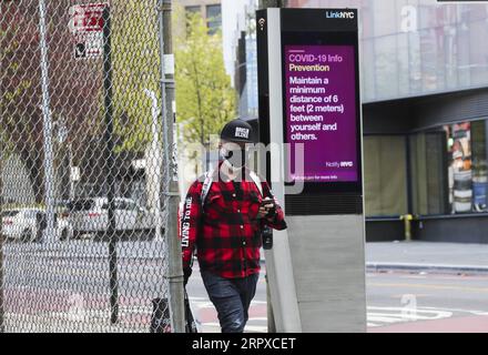 200517 -- PECHINO, 17 maggio 2020 -- Un uomo cammina davanti a uno schermo elettronico che mostra le indicazioni per la prevenzione del COVID-19 a Brooklyn di New York, negli Stati Uniti, 11 maggio 2020. PER ANDARE CON I TITOLI DI XINHUA DEL 17 MAGGIO 2020 U.S.-COVID-19-CONTROVERSAL HANDLING WANGXYING PUBLICATIONXNOTXINXCHN Foto Stock