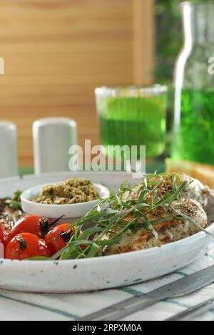 Pollo gustoso, verdure con dragoncello e pesto serviti al tavolo, primo piano Foto Stock