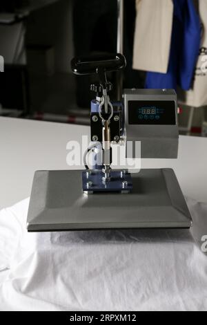 Stampa logo. Pressa a caldo con t-shirt su tavolo bianco Foto Stock