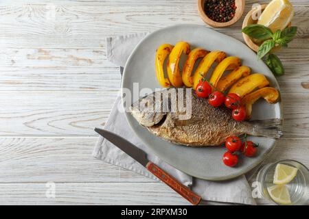 Delizioso pesce dorado arrosto servito con verdure su un tavolo di legno, piatto. Spazio per il testo Foto Stock