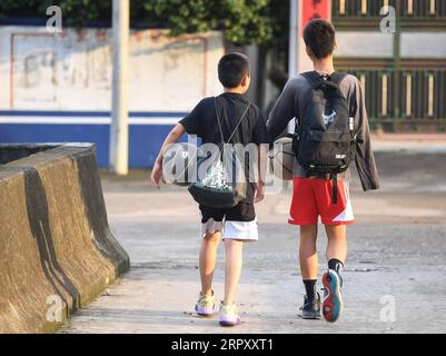 200605 -- YUNFU, 5 giugno 2020 -- Zhang Jiacheng R insieme al suo compagno di scuola a piedi per la scuola nella città di Gaocun della città di Yunfu, nella provincia del Guangdong della Cina meridionale, 4 giugno 2020. ANDARE CON un giocatore di basket cinese con un braccio solo di 13 anni diventa Internet Sensation CHINA-GUANGDONG-YUNFU CITY-DISABLED BOY-BASKET CN DengxHua PUBLICATIONxNOTxINxCHN Foto Stock