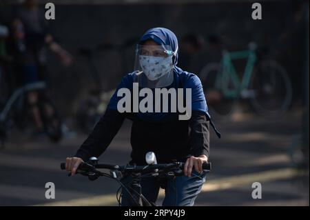 200614 -- GIACARTA, 14 giugno 2020 -- Una donna che indossa uno scudo facciale cavalca una bicicletta in Sudirman Street a Giacarta, Indonesia, 14 giugno 2020. INDONESIA-GIACARTA-COVID-19-ATTIVITÀ-EASING VerixSanovri PUBLICATIONxNOTxINxCHN Foto Stock