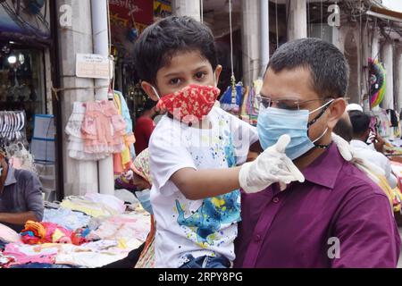 200620 -- DACCA, 20 giugno 2020 Xinhua -- Un uomo che tiene un bambino cammina fuori da un mercato di strada a Dacca, Bangladesh, il 20 giugno 2020. Il Bangladesh ha riportato oltre 3.240 casi di COVID-19 in più sabato, portando il totale nel paese a oltre 108.000. Str/Xinhua BANGLADESH-DACCA-COVID-19 PUBLICATIONxNOTxINxCHN Foto Stock