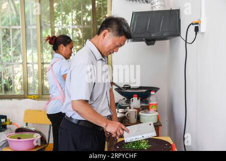 200625 -- NINGMING, 25 giugno 2020 -- Jiao Shengding e sua moglie Zhao Damei cucinano pranzo per gli studenti in un sito di insegnamento nella contea di Ningming, nella regione autonoma del Guangxi Zhuang della Cina meridionale, 23 giugno 2020. Jiao Shengding, 52 anni, è l'unico insegnante presso il sito di insegnamento del villaggio di Zhangji, che si trova al confine tra Cina e Vietnam. Dopo essersi diplomato presso la scuola professionale secondaria della contea nel 1990, Jiao ha scelto di essere un insegnante presso il villaggio di Zhangji e da allora ha insegnato lì per 30 anni. Negli ultimi tre decenni, ha insegnato più di 40 Foto Stock