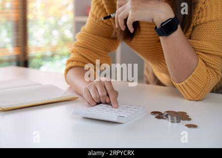 Donna stressata che cerca di gestire documenti finanziari, avendo problemi a trovare soldi per pagare bollette o prestiti Foto Stock