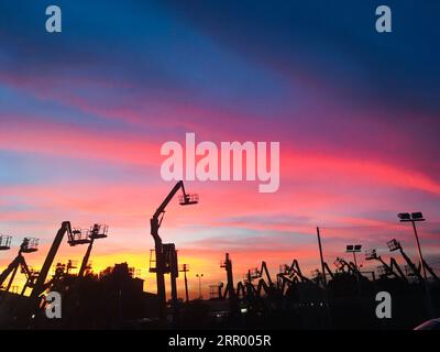 Un cantiere al tramonto, illuminato da un vivace cielo rosa e blu Foto Stock