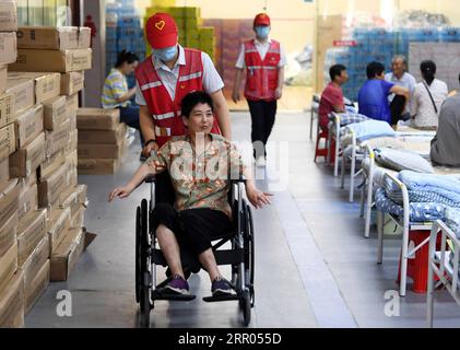 200729 -- HEFEI, 29 luglio 2020 -- Un volontario spinge la sedia a rotelle di un abitante del villaggio in un rifugio temporaneo nella No.168 Middle School di Hefei, nella provincia di Anhui della Cina orientale, 29 luglio 2020. Colpiti dalle inondazioni, più di 300 abitanti del villaggio a Sanhe Town di Hefei sono stati trasferiti alla scuola. Pasti gratuiti, consulenza psicologica e assistenza quotidiana sono forniti nel rifugio. CHINA-ANHUI-HEFEI-FLOOD-TEMPORARY SHELTER CN LIUXJUNXI PUBLICATIONXNOTXINXCHN Foto Stock