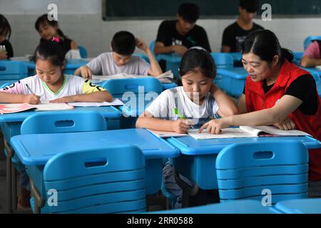 200729 -- HEFEI, 29 luglio 2020 -- Un tutor volontario fa una ragazza in un rifugio temporaneo in una scuola nella contea di Feixi, nella provincia di Anhui della Cina orientale, 29 luglio 2020. Colpiti dalle inondazioni, oltre 200 abitanti del villaggio a Fengle Town di Hefei furono trasferiti alla scuola. I volontari del rifugio temporaneo hanno contribuito al trasporto di materiali di soccorso contro le inondazioni, distribuzione di cibo, servizi sanitari, tutoraggio per i compiti e servizi gratuiti di parrucchiere. CHINA-ANHUI-HEFEI-FLOOD-VOLONTARIATO CN LIUXJUNXI PUBLICATIONXNOTXINXCHN Foto Stock