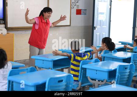 200729 -- HEFEI, 29 luglio 2020 -- Un volontario insegna a cantare ai bambini in un rifugio temporaneo in una scuola della contea di Feixi, nella provincia di Anhui della Cina orientale, 29 luglio 2020. Colpiti dalle inondazioni, oltre 200 abitanti del villaggio a Fengle Town di Hefei furono trasferiti alla scuola. I volontari del rifugio temporaneo hanno contribuito al trasporto di materiali di soccorso contro le inondazioni, distribuzione di cibo, servizi sanitari, tutoraggio per i compiti e servizi gratuiti di parrucchiere. CHINA-ANHUI-HEFEI-FLOOD-VOLONTARIATO CN LIUXJUNXI PUBLICATIONXNOTXINXCHN Foto Stock