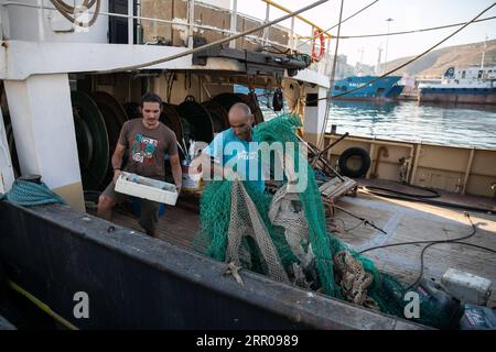 200803 -- PIREO GRECIA, 3 agosto 2020 Xinhua -- l'imprenditore greco Lefteris Arapakis L tiene una scatola di rifiuti di plastica mentre un pescatore si deposita le sue reti nel Pireo, Grecia, il 31 luglio 2020. Un'organizzazione greca sta addestrando i pescatori locali a raccogliere i rifiuti di plastica dal mare per proteggere la diminuzione degli stock ittici nel Mediterraneo. Foto di Lefteris Partsalis/Xinhua TO GO WITH Feature: Pescatori greci addestrati a pescare plastica per proteggere i pesci GRECIA-PIREO-RACCOLTA RIFIUTI MARINI PUBLICATIONxNOTxINxCHN Foto Stock