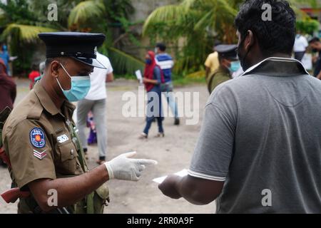 200805 -- COLOMBO, 5 agosto 2020 -- Un votante R ha il suo documento di identificazione controllato in un seggio elettorale a Colombo, Sri Lanka, 5 agosto 2020. Un'affluenza alle urne stimata del 40% è stata registrata nelle elezioni parlamentari dello Sri Lanka entro mezzogiorno di mercoledì, dopo che le votazioni sono iniziate alle 7 di mattina ora locale, ha detto il dipartimento di informazione del governo. SRI LANKA-PARLIMENTARY ELEZIONI-VOTO TangxLu PUBLICATIONxNOTxINxCHN Foto Stock