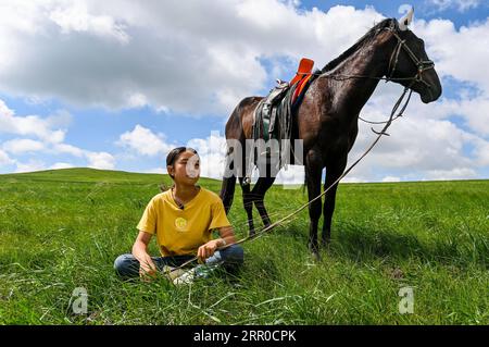 200809 -- XILIN GOL, 9 agosto 2020 -- Xilinhua si riposa sulla prateria Baiyinxile a Xilinhot, nella regione autonoma della Mongolia interna della Cina settentrionale, 4 agosto 2020. La vazione estiva è stata il periodo dell'anno preferito da Xilinhua. Per frequentare la scuola media, la quattordicenne vive la maggior parte del tempo con i suoi nonni nel centro di Xilinhot, separati dai suoi genitori che gestiscono un ranch sul pascolo di Baiyinxile. Pertanto, l'estate significa sia relax che ricongiungimento al settimo elementare. Il padre di Xilinhua, Gangsuhe, è un famoso cavaliere. Imparando da lui, Xilinhua aveva anche padroneggiato le abilità equestri Foto Stock