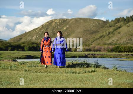 200810 -- HULUN BUIR, 10 agosto 2020 -- Aijim L e sua madre Uran camminano lungo un fiume in Ewenki Autonomous Banner, regione autonoma della Mongolia interna della Cina settentrionale, 6 agosto 2020. Aijim è una ragazza post-90 del gruppo etnico Ewenki che vive nella regione autonoma della Mongolia interna. Nel 2014, è tornata nella sua città natale a Ewenki Autonomous Banner, Hulun Buir City, dopo la laurea all'università, e ha aiutato sua madre Uran a gestire uno studio di artigianato. Realizzano oggetti di artigianato a tema Sun Flower e aprono attività online per vendere i prodotti. Dietro l'artigianato che abbiamo fatto c'e' la storia popolare di Sun Girl Who Foto Stock