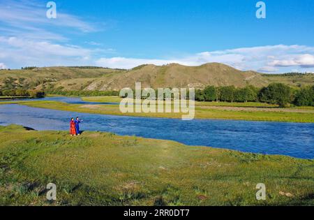 200810 -- HULUN BUIR, 10 agosto 2020 -- Aijim L e sua madre Uran camminano lungo un fiume in Ewenki Autonomous Banner, regione autonoma della Mongolia interna della Cina settentrionale, 6 agosto 2020. Aijim è una ragazza post-90 del gruppo etnico Ewenki che vive nella regione autonoma della Mongolia interna. Nel 2014, è tornata nella sua città natale a Ewenki Autonomous Banner, Hulun Buir City, dopo la laurea all'università, e ha aiutato sua madre Uran a gestire uno studio di artigianato. Realizzano oggetti di artigianato a tema Sun Flower e aprono attività online per vendere i prodotti. Dietro l'artigianato che abbiamo fatto c'e' la storia popolare di Sun Girl Who Foto Stock