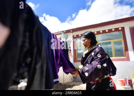 200820 -- GOLOG, 20 agosto 2020 -- Villager Degyi asciuga i vestiti nel suo cortile nel villaggio Ghadan di Machali Township, contea di Madoi, prefettura autonoma tibetana di Golog, provincia del Qinghai della Cina nord-occidentale, 19 agosto 2020. A partire da ottobre 2018, un totale di 1.036 residenti colpiti dalla povertà registrati si sono trasferiti dalle terre meno ospitali della contea di Madoi a Ghadan, un villaggio di trasferimento appena costruito all'interno dell'area sorgente del fiume giallo. Il nuovo villaggio ha un trasporto migliore che rende più facile per gli abitanti del villaggio trovare lavoro o avviare attività in altre città. Nel frattempo, molti abitanti del villaggio vengono pagati come invidio Foto Stock