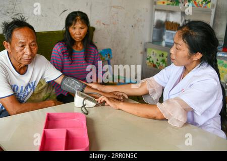 200821 -- LONGLI, 21 agosto 2020 -- Luo Mu misura la pressione sanguigna per un abitante del villaggio di Cuiwei nella contea di Longli, prefettura autonoma di Qiannan Buyi-Miao, provincia di Guizhou della Cina sud-occidentale, 18 agosto 2020. Luo Mu, 49 anni, medico del gruppo etnico Buyi, lavora nel villaggio di Cuiwei della contea di Longli. Laureata in medicina nel 2004, è tornata al villaggio come medico. Trasformò il suo soggiorno in una clinica con le attrezzature mediche che aveva acquistato, per curare i pazienti del villaggio. Nel 2007, Luo fu impiegato in una clinica di nuova fondazione nel villaggio con una populatio Foto Stock