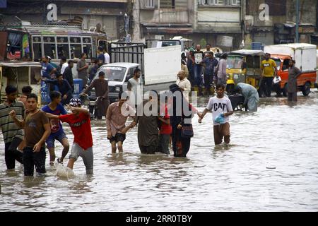 200826 -- KARACHI, 26 agosto 2020 -- le persone si sono gettate attraverso le acque alluvionali dopo le forti piogge monsoniche nella città pakistana meridionale di Karachi il 25 agosto 2020. Le forti piogge monsoniche hanno superato un record di downpour di 36 anni nel mese di agosto nella capitale Karachi, nella provincia meridionale del Sindh del Pakistan, ha detto il Dipartimento meteorologico del Pakistan. Le forti piogge hanno devastato diverse parti della città, dove l'acqua piovana ha causato inondazioni, sommerse strade, strade, veicoli e zone basse. Anche gli incidenti legati alla pioggia, tra cui folgorazione e crollo del tetto, hanno causato la morte di quattro persone Foto Stock