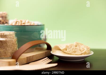 Hummus classico su un piccolo piatto su un tavolo di legno. Sfondo verde. Foto Stock