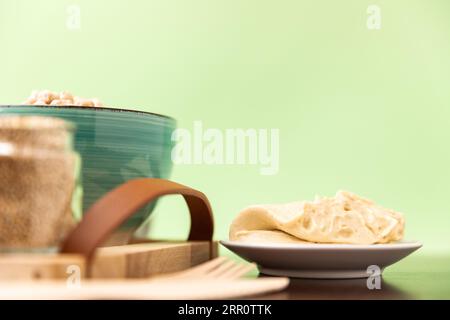 Hummus classico su un piccolo piatto su un tavolo di legno. Sfondo verde. Foto Stock