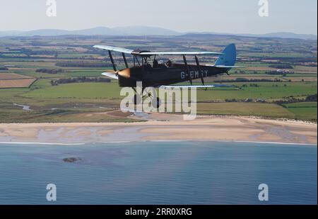 L'aereo d'epoca Tiger Moth della seconda guerra mondiale prende il volo sul Northumberland. Il DH82A Tiger Moth, costruito nel 1940, di proprietà di Darren Davis e Dave Burns della Tiger Flights, un'azienda indipendente con sede all'Eshott Airfield. Tempo permettendo, la G-EMSY volerà tutto l'anno, offrendo agli appassionati di aviazione l'esperienza senza precedenti di volo a cabina aperta e una vista unica del paesaggio del Northumberland e dei monumenti storici più rappresentativi. Data immagine: Martedì 5 settembre 2023. Foto Stock