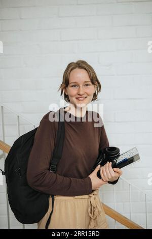 Ritratto di una giovane donna felice con zaino e cartellina all'università Foto Stock