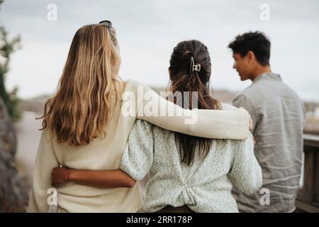Vista posteriore delle amiche che camminano con le braccia intorno Foto Stock