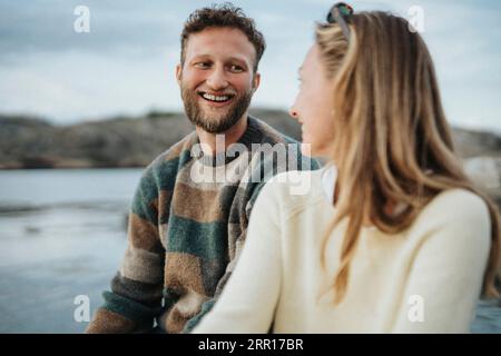Felice giovane uomo che si diverte con un'amica donna vicino al lago Foto Stock