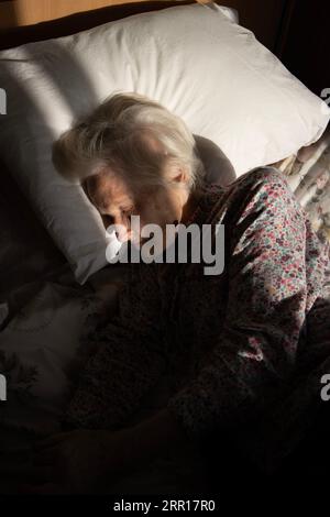 Donna anziana addormentata sul suo letto di casa di cura, Inghilterra, Regno Unito Foto Stock