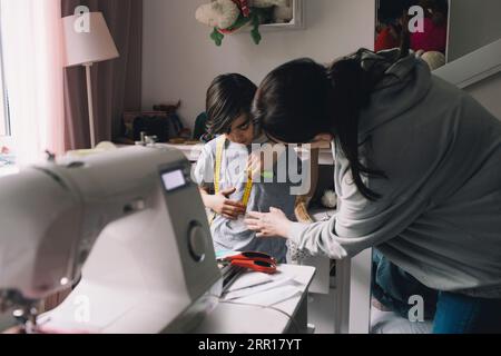 Madre che cuce vestiti per figlio a casa Foto Stock